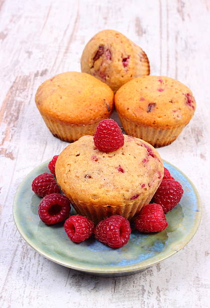 istock Fresh baked muffins with raspberries on old wooden background 616895538