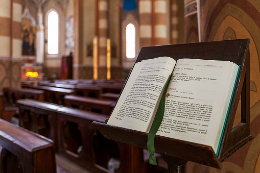 Alba, Italy - May 11, 2015: Open Bible on the stand inside San Lorenzo Cathedral (aka Duomo) - biggest and one of the important cathedrals in town of Alba dedicated to Saint Lawrence.