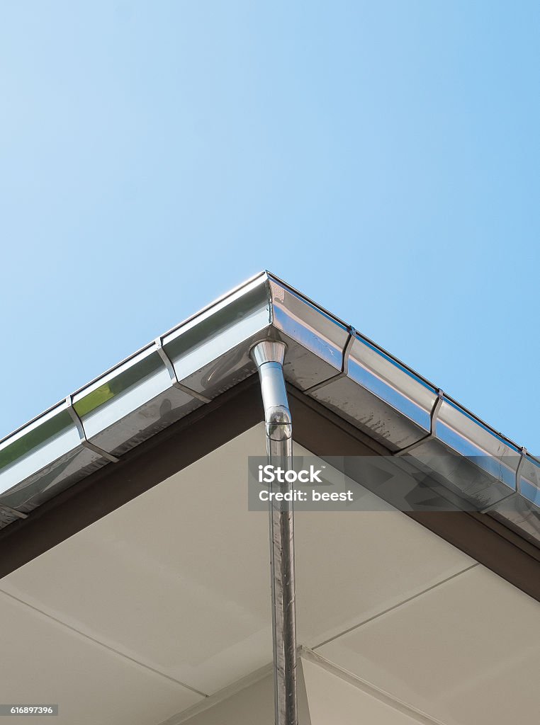 Rain gutter system on roof of House Rain gutter system on roof of House against Blue Sky -  Can use for illustration product Rooftop Stock Photo