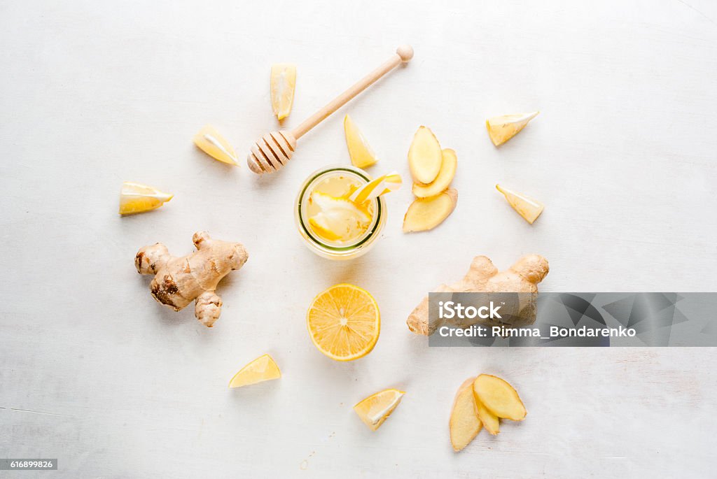 Ginger-lemon drink in a bottle with a straw Ginger-lemon drink in a bottle with a straw. Selection of the ingredients of ginger cocktail or tea: ginger root, lemon, honey. On white table. Top View,copy space Ginger - Spice Stock Photo
