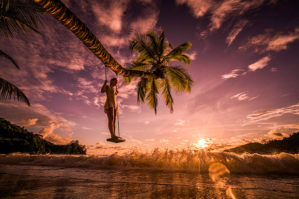 istock Below view of a woman on swing at sunset beach. 616901270