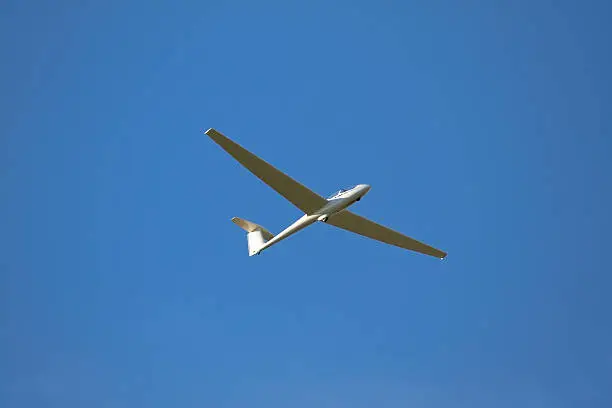 A sailplane in front of a blue sky glides through the air without its own motor drive.