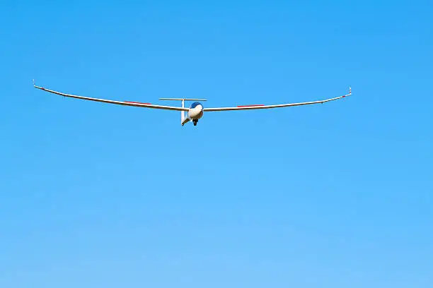 A sailplane in front of a blue sky glides through the air without its own motor drive.