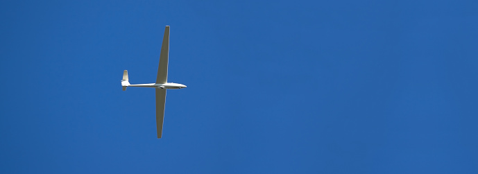 A sailplane in front of a blue sky glides through the air without its own motor drive.