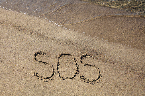 SOS sign on sandy beach