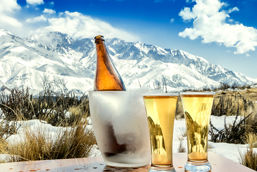 Glasses and bottle of fresh beer, as a background, the  snowy mountains.