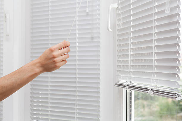 adjusting the white blinds in height use a cord - sunblinds imagens e fotografias de stock