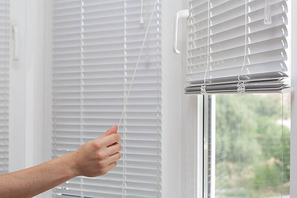 istock Girls hand raise the white blinds with a cord 616906908
