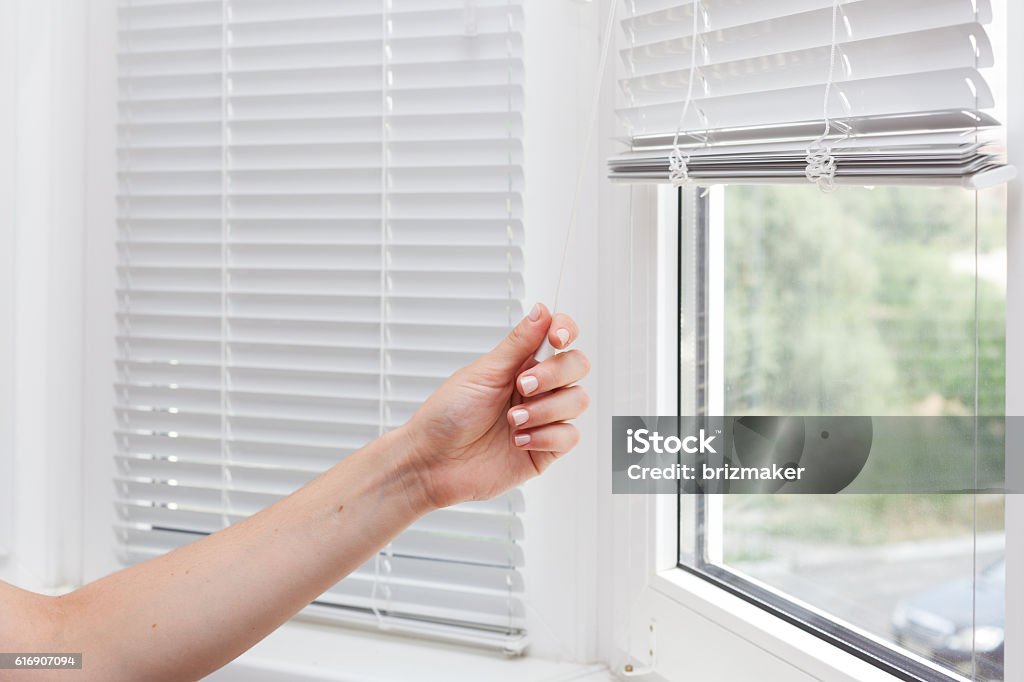 Adjusting the white blinds in height use a cord Window Blinds Stock Photo