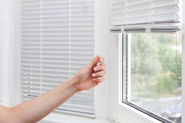 adjusting the white blinds in height use a cord - sunblinds imagens e fotografias de stock