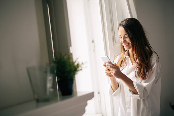 istock Beautiful woman using phone in house 617351910