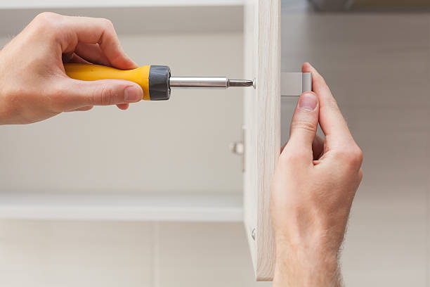 istock The worker sets a new handle on the white cabinet 617353832