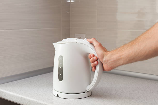 istock White electric Kettle in hand 617354186