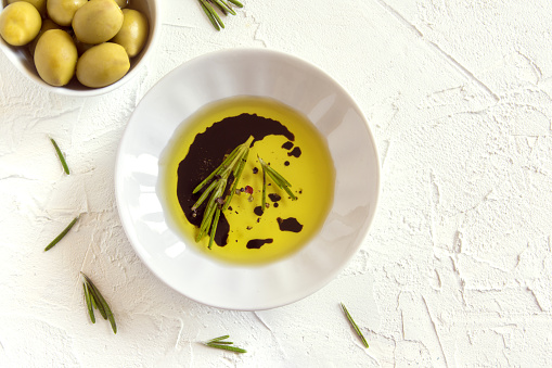 Organic olive oil with rosemary, balsamic vinegar and spices over white stone background with copy space, healthy food concept