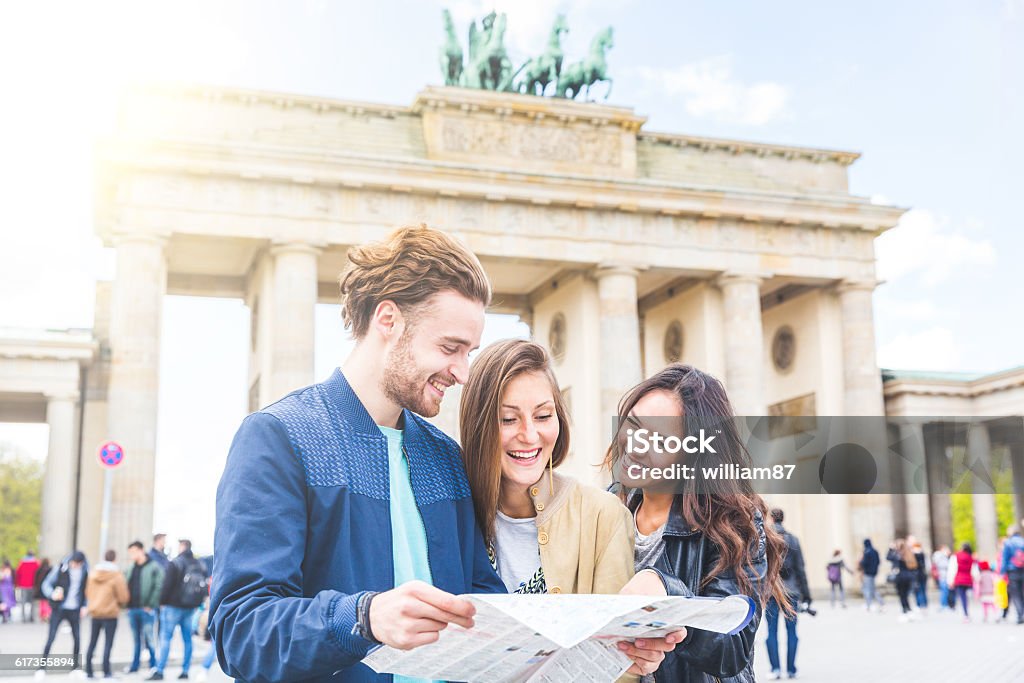 Multiracial group of friends having a coffee together Multiracial group of friends visiting the city of Berlin. Two women and a man looking at a map with Brandenburg Gate on background. Lifestyle, friendship and tourism concepts with real people models. Berlin Stock Photo