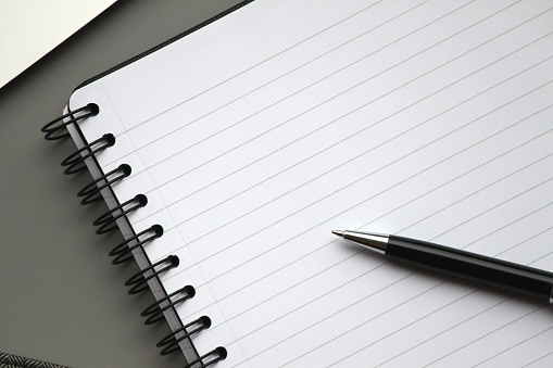 Close up shot of a lined notepad with pen with space to add text