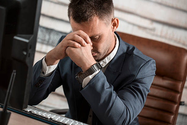 istock Tired business man at workplace in office holding his head 617356586