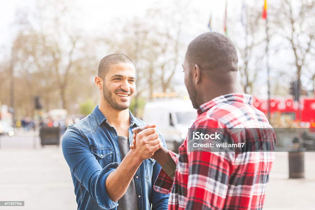 Two men giving a friendly handshake Two men giving a friendly handshake. A black man meeting his middle eastern friend and greets him in London. Friendship and lifestyle concepts. Friendship Stock Photo