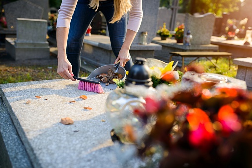 Woman cleans a grave. November 1 All Saints' Day