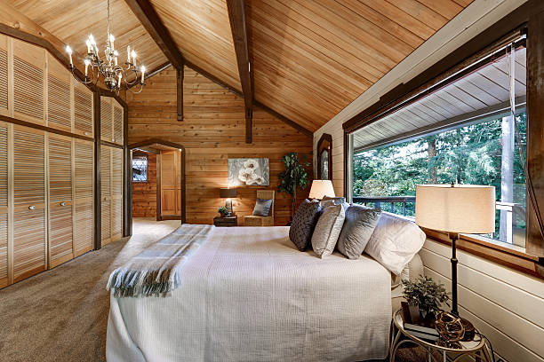 Wooden bedroom interior with high vaulted ceiling, grey carpet floor and large floor to ceiling wardrobe.  Northwest, USA