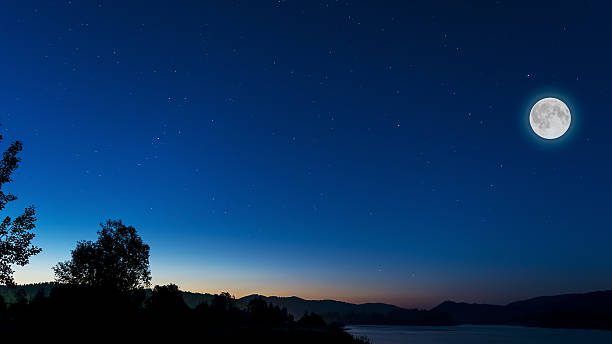 istock Midnight sky with full moon above river landscape 617359770