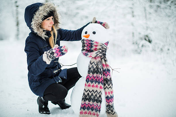 istock Young woman building snowman 617360114