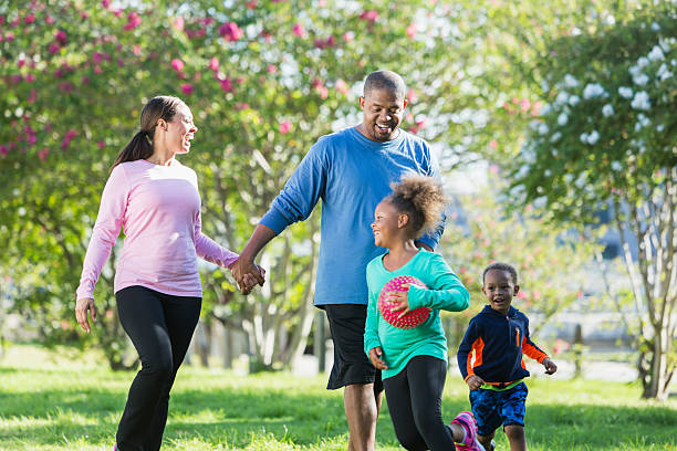 Black parents walking in park, children running, playing