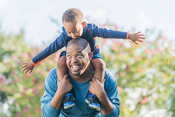 istock Little boy sitting on father's shoulders 617362226