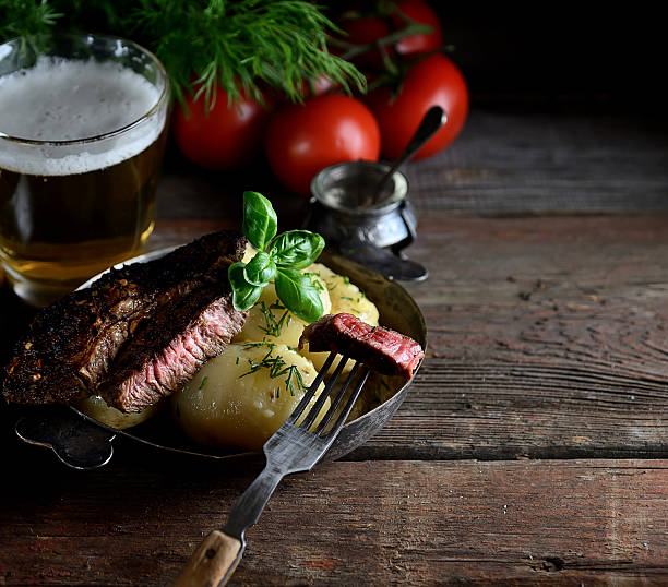 boiled potatoes, meat and tomatoes on a wooden background