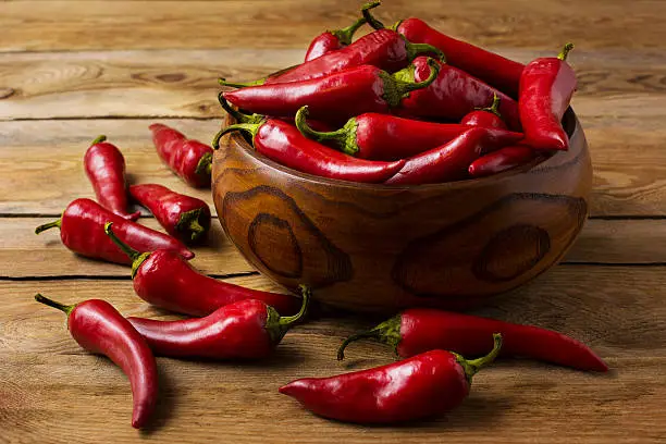 Photo of Red hot chilli pepper in wooden bowl