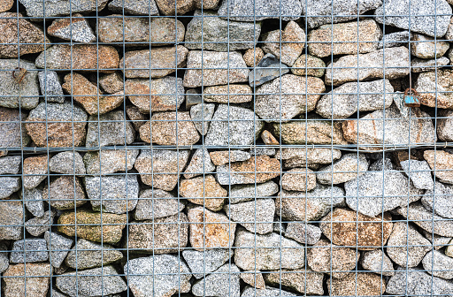 Wire Gabion Rock Fence. Metal Cage filled with rocks. Texture background of rock fence with cage.