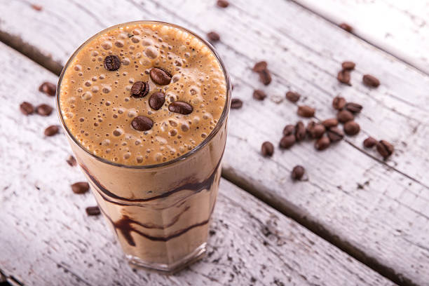 Cold chocolate milkshake frappe in tall glass with ice stock photo