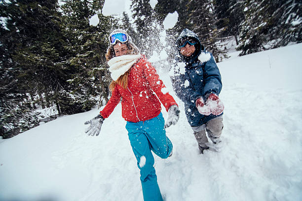 Snowballs playing in winter forest. Family mother and daughter having fun throwing snow outdoors. people relaxing during holidays