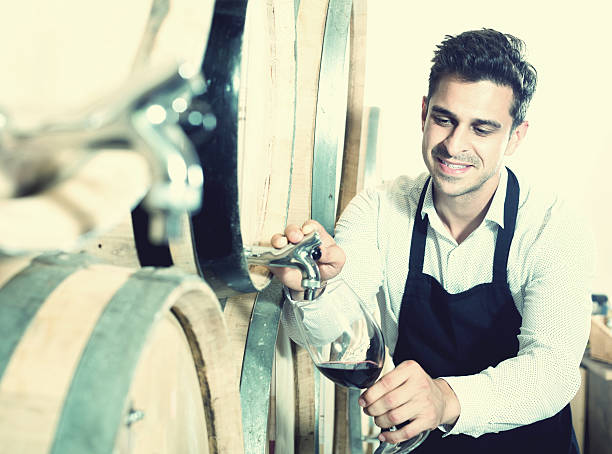 istock Seller pouring wine in cellar 617369748