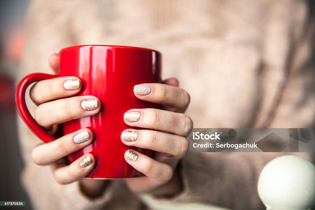 Woman's hand holding red cup of coffee Woman's hand holding a red cup of coffee. With a beautiful winter manicure. Drink, fashion, morning Adult Stock Photo