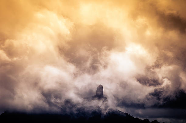 Big rock surrounded by clouds at sunset stock photo