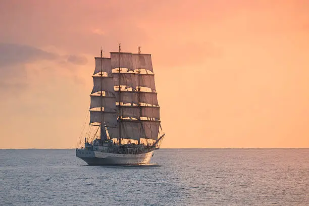 Ancient sailing ship in the sea at sunset