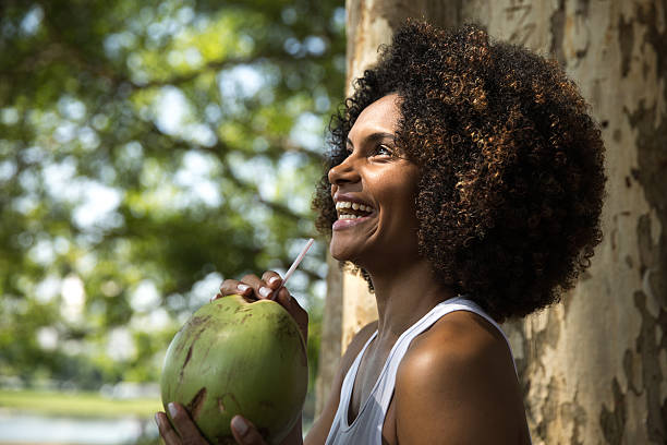 Brazilian woman drinking coconut water in the park People Collection fruit of coconut tree stock pictures, royalty-free photos & images
