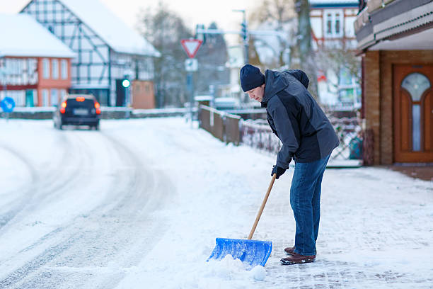 istock Man with snow shovel cleans sidewalks in winter 617382832
