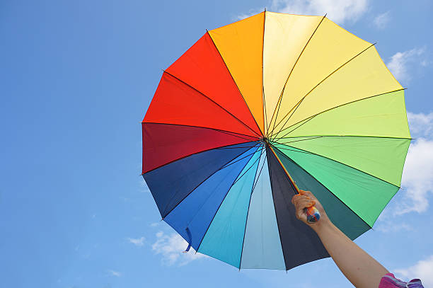 istock Female hand holding multicolored umbrella against the sunny sky 617387584
