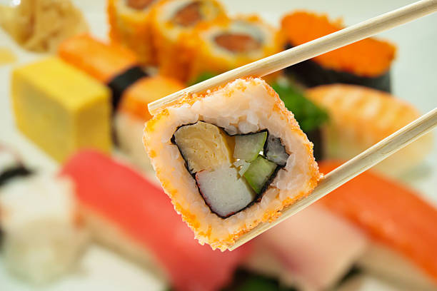 istock Sushi in chopsticks with blur sushi on plate background 617389990