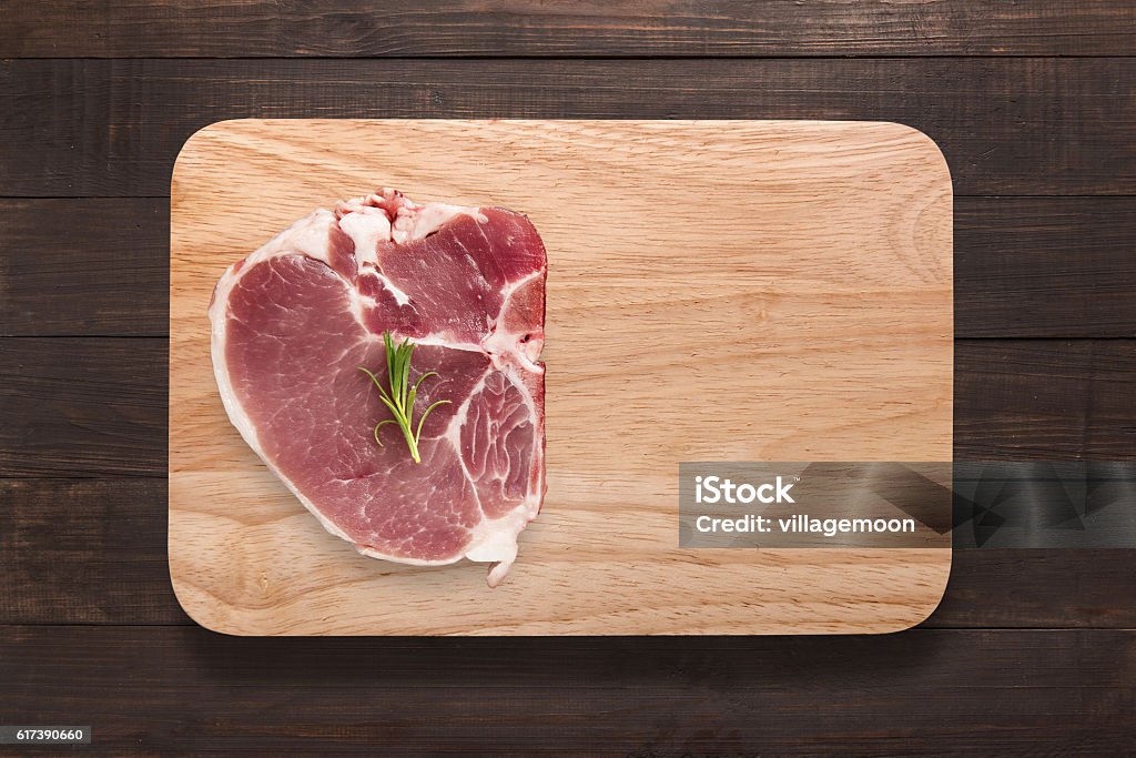 Top view raw pork chop steak on cutting board. Top view raw pork chop steak on cutting board on wooden background. Copyspace for your text. Block Shape Stock Photo