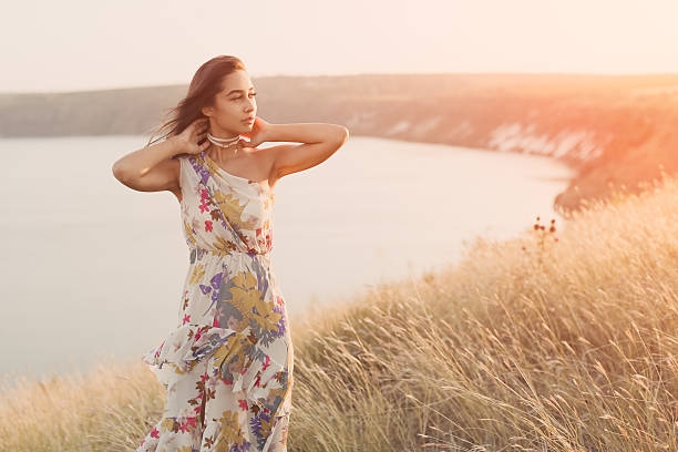Beautiful girl in meadow with sun rays. Young woman posing outdoors at nature with copy space
