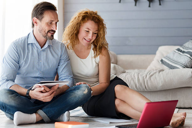 istock Nice couple sitting in floor and looking at laptop 617393876
