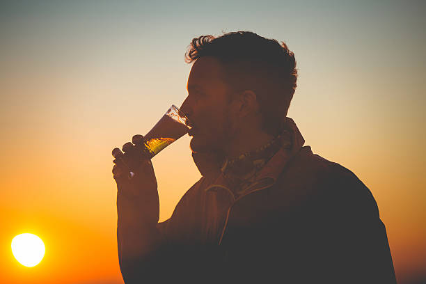 Happy Young Man Drinking Beer after Cross-Country Running, Alps, Europe Happy young man drinking beer after running uphill on the mountain Sabotin in Julian Alps, Slovenia-Italy border, Europe. Sunset. Autumnal colors, golden hour.  Nikon D800, full frame, XXXL. golden hour drink stock pictures, royalty-free photos & images