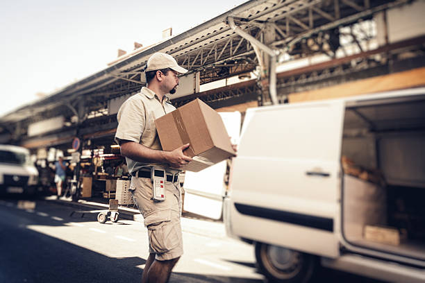 messenger delivering parcel, walking in street next to his van - postal worker truck driver delivering delivery person imagens e fotografias de stock