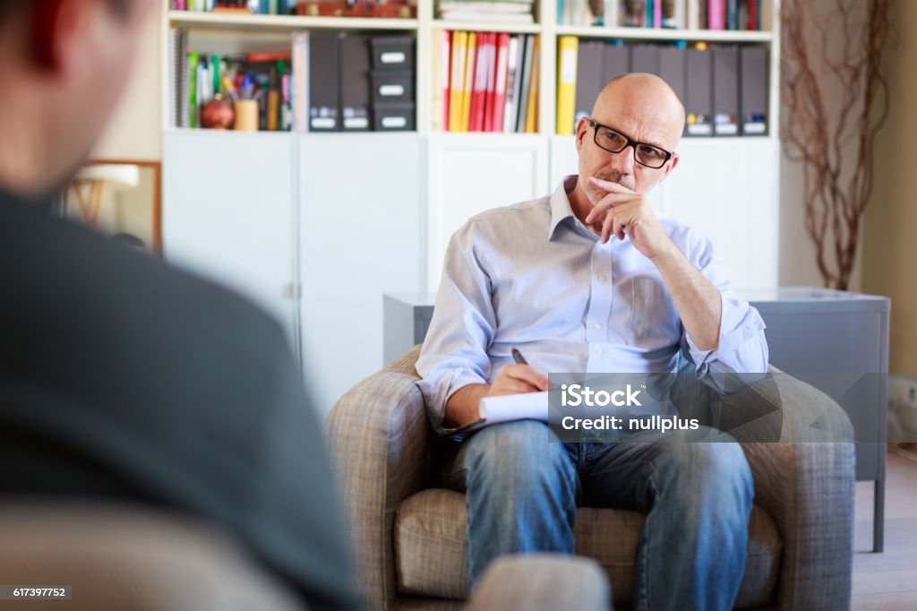 Therapy session, adult man talking to his psychotherapist Psychotherapy Stock Photo