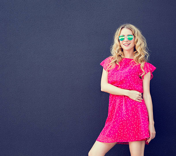 Summer Fashion Woman in Pink Dress at Dark Wall stock photo