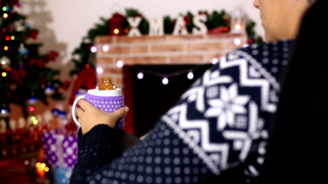 Woman resting with cup of hot drink near fireplace