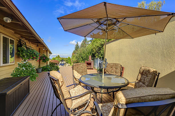 istock Patio table set with opened umbrella. Wooden walkout deck 617570006